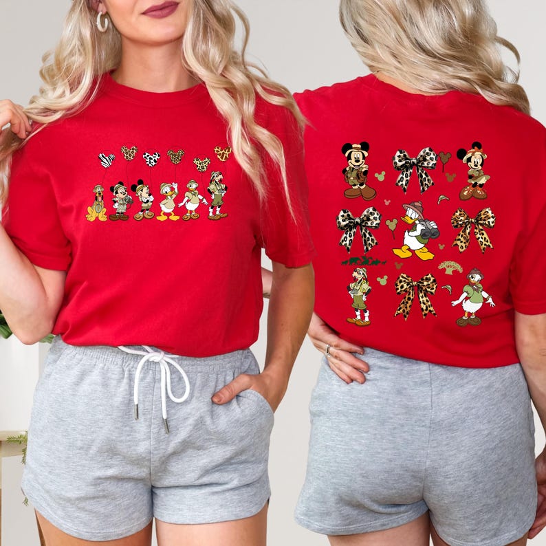 May include: Two red t-shirts with a Disney character design. The front of the shirt features a line of Disney characters wearing safari outfits. The back of the shirt features a pattern of Disney characters, bows, and hearts.