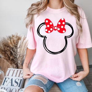 May include: Pink t-shirt with a black outline of Mickey Mouse's head and a red bow with white polka dots.