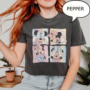 Puede incluir: Camiseta gris oscuro con un gr&aacute;fico de cuatro paneles de Minnie Mouse en varias poses, cada una sobre un fondo pastel. La palabra "PEPPER" est&aacute; en un bocadillo. La camiseta tiene mangas cortas y cuello redondo.