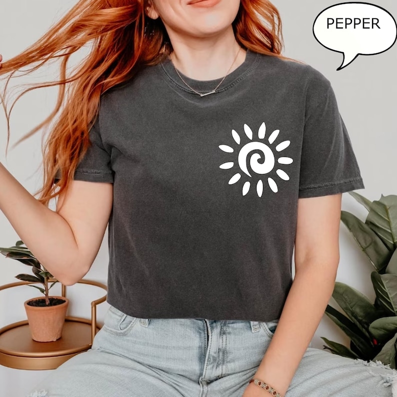 May include: A dark gray cropped t-shirt with a white sun graphic and the word "PEPPER" in a speech bubble.