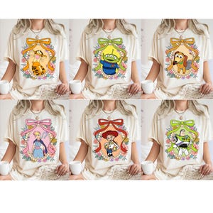 May include: Six different t-shirts featuring a variety of Disney characters in a vintage-inspired frame with a pearl and floral border. The characters include Buzz Lightyear, Woody, Jessie, Rex, Slinky Dog, and Tigger.