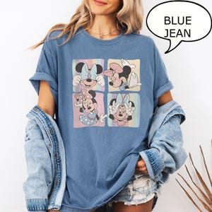 Puede incluir: Camiseta vaquera azul con cuatro cuadrados con ilustraciones de Minnie Mouse en colores pastel. La camiseta tiene las mangas enrolladas y un bocadillo con el texto "BLUE JEAN".