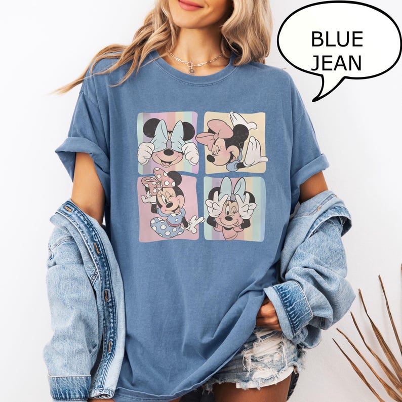 Puede incluir: Camiseta vaquera azul con cuatro cuadrados con ilustraciones de Minnie Mouse en colores pastel. La camiseta tiene las mangas enrolladas y un bocadillo con el texto "BLUE JEAN".