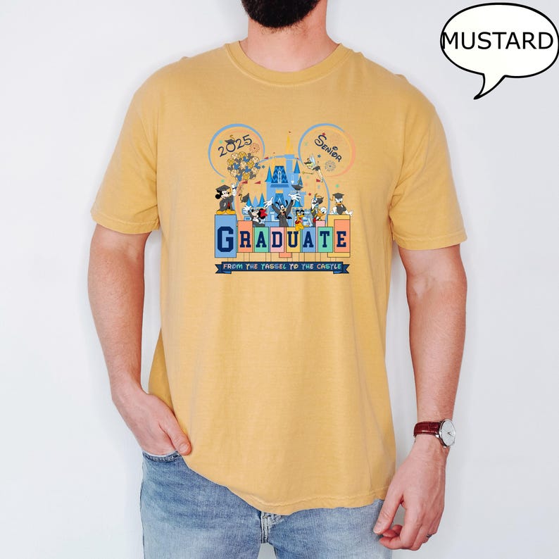 以下が含まれることがあります： マスタードイエローのTシャツに、ディズニーワールドで卒業を祝うミッキーマウスとその仲間たちのグラフィックがプリントされています。Tシャツには「Graduate from the tassel to the castle」と「2025 Senior」の文字が書かれています。