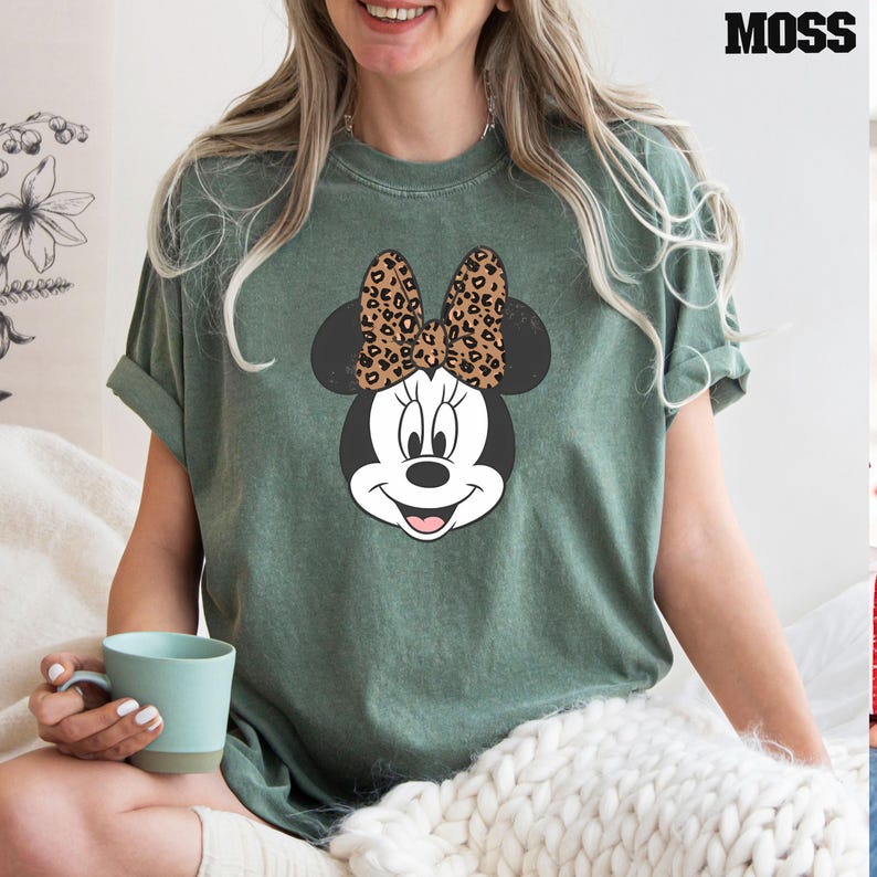 May include: A green t-shirt with a cartoon image of Minnie Mouse wearing a leopard print bow.