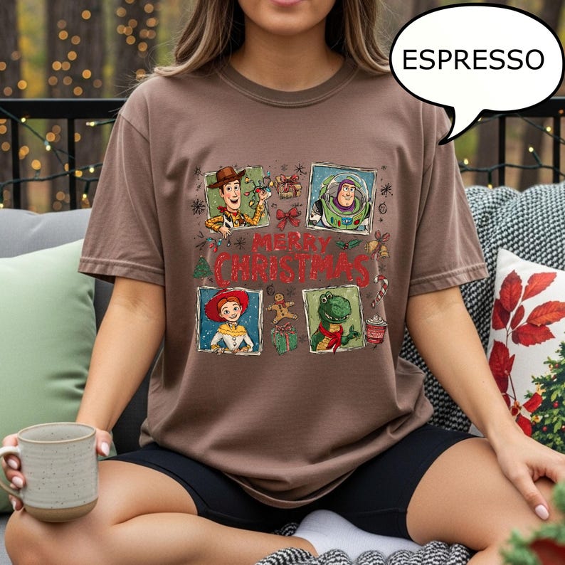 May include: Espresso-colored t-shirt featuring a graphic of cartoon characters with the text "MERRY CHRISTMAS". The design includes images of Woody, Buzz Lightyear, Jessie, and Rex. The shirt is a comfortable, casual style.