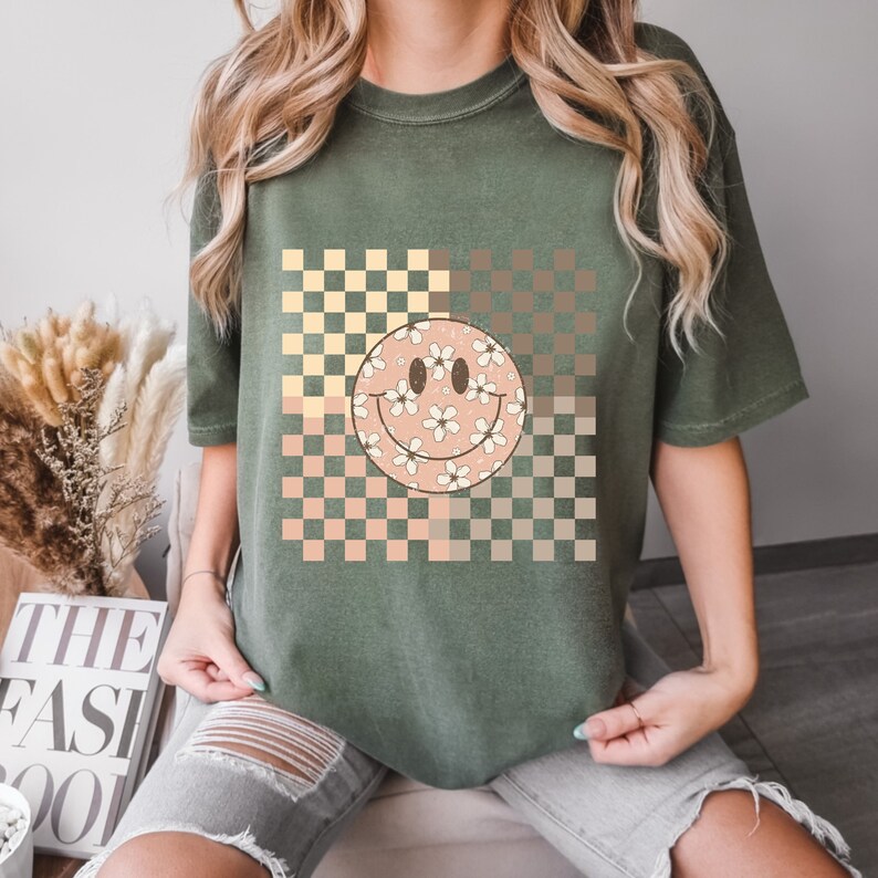 Peut inclure: Un t-shirt vert avec un motif &agrave; carreaux et un smiley floral.