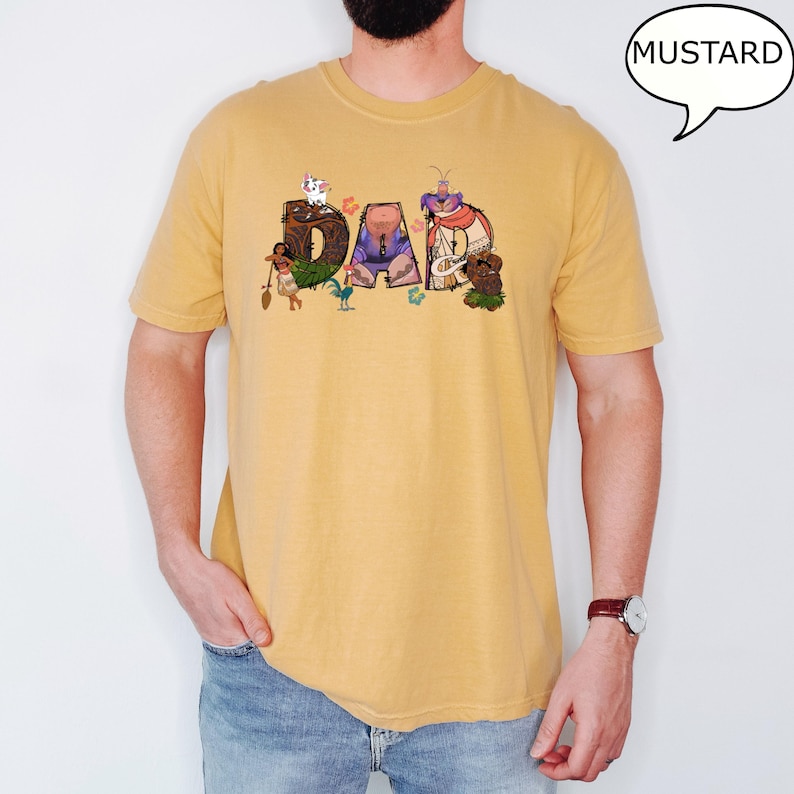 May include: A mustard yellow t-shirt featuring a graphic of characters from the film Moana spelling out the word "DAD".