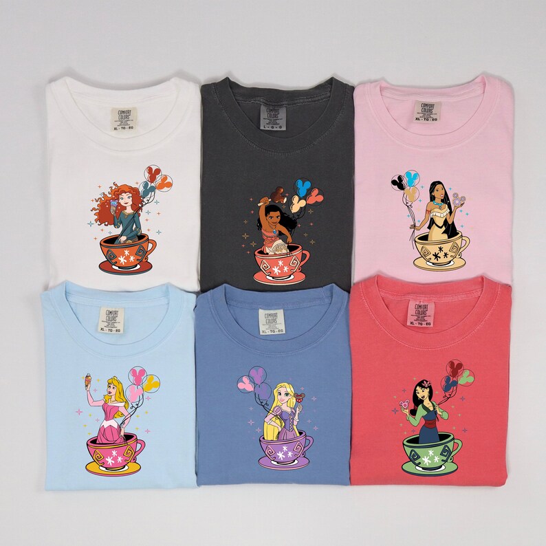 May include: Six different colored t-shirts featuring Disney princesses in teacups with balloons. The princesses are:  Ariel, Pocahontas, Mulan, Tiana, Belle, and Rapunzel.