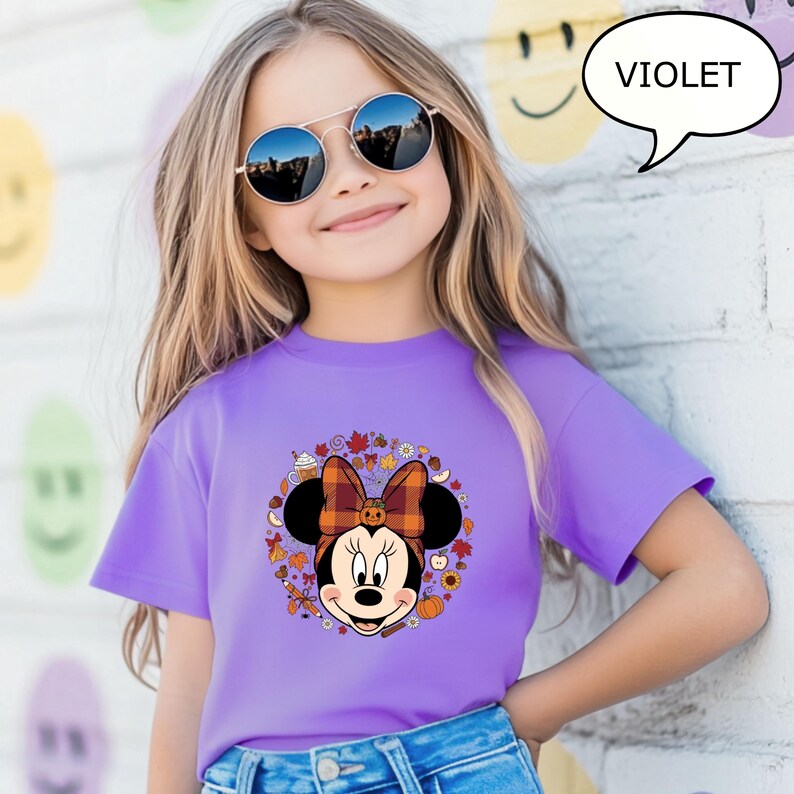 May include: A violet t-shirt featuring a Minnie Mouse graphic with a fall-themed design. The graphic includes a plaid bow, pumpkins, and autumn leaves. The word "VIOLET" is in a speech bubble.