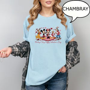 Puede incluir: Camiseta azul claro con un dise&ntilde;o de San Valent&iacute;n con Mickey y Minnie Mouse, el Pato Donald y Goofy. El dise&ntilde;o incluye corazones y el texto "Mickey's Very Happy Valentine's Day". La camiseta es de color chambray.