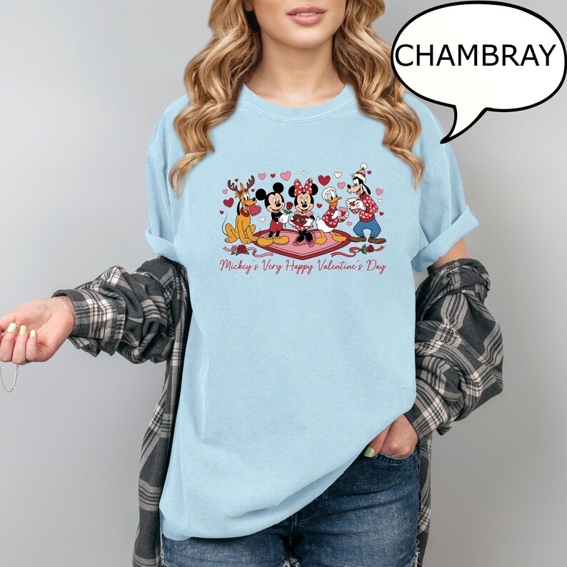 Puede incluir: Camiseta azul claro con un dise&ntilde;o de San Valent&iacute;n con Mickey y Minnie Mouse, el Pato Donald y Goofy. El dise&ntilde;o incluye corazones y el texto "Mickey's Very Happy Valentine's Day". La camiseta es de color chambray.