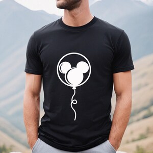 Pode incluir: Camiseta preta com um gr&aacute;fico branco de uma cabe&ccedil;a do Mickey Mouse dentro de um bal&atilde;o.