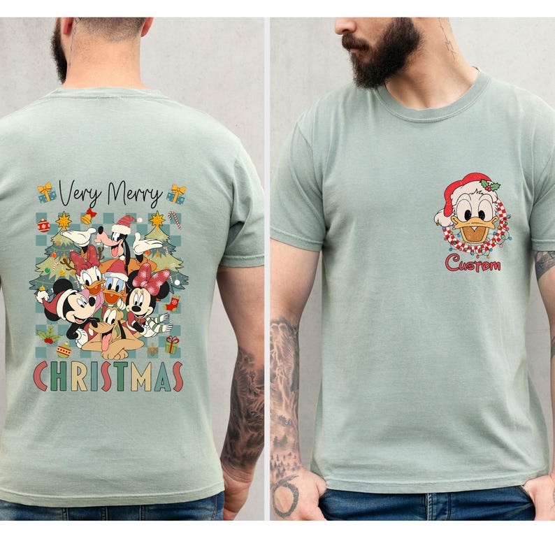 Pode incluir: Camiseta verde claro com um design de Natal colorido. As costas apresentam personagens da Disney, incluindo Mickey e Minnie, com a frase "Very Merry Christmas". A frente apresenta o Pato Donald e a palavra "Custom".