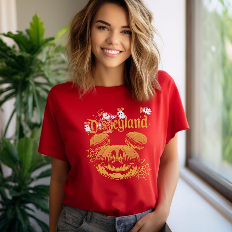 May include: Red t-shirt with a pumpkin Mickey Mouse design and the text "Disneyland" in white. There are also small ghosts and Mickey Mouse heads around the pumpkin Mickey Mouse.
