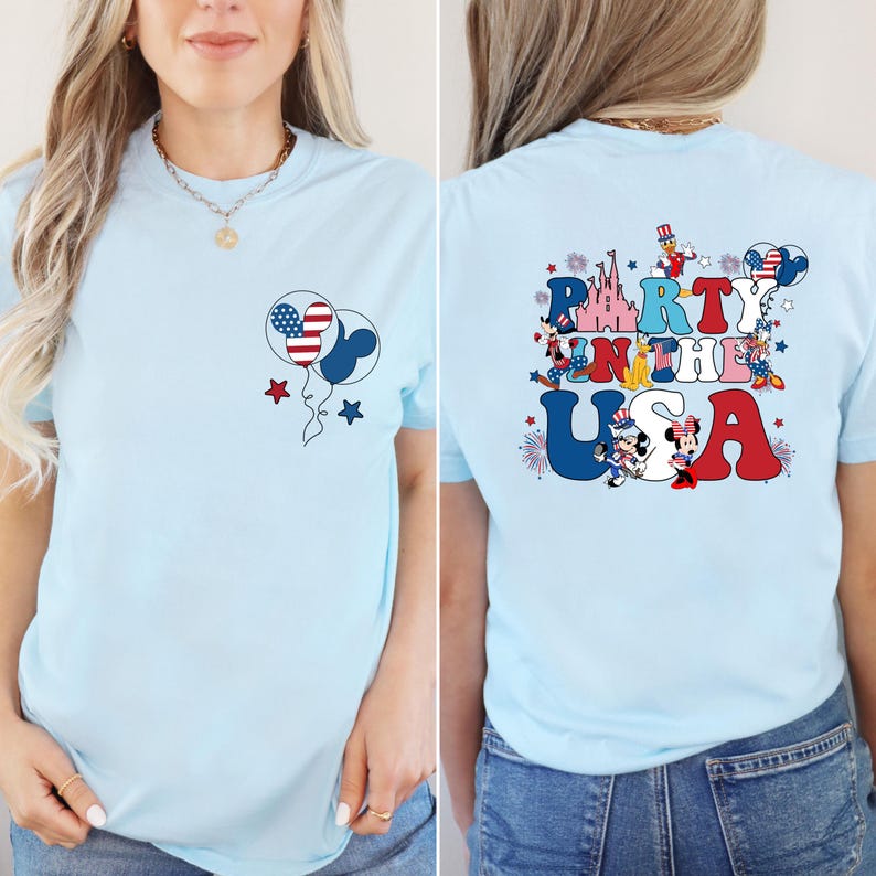 K&ouml;nnte beinhalten: Hellblaues T-Shirt mit patriotischem Design. Die Vorderseite zeigt zwei Ballons mit einem amerikanischen Flaggenmuster und Sternen. Auf der R&uuml;ckseite des Shirts steht "Party in the USA" mit Zeichentrickfiguren und Feuerwerk.