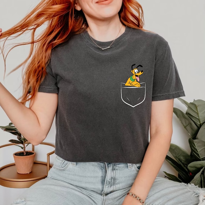 May include: A dark gray cropped t-shirt with a white pocket featuring a cartoon image of Pluto the dog.