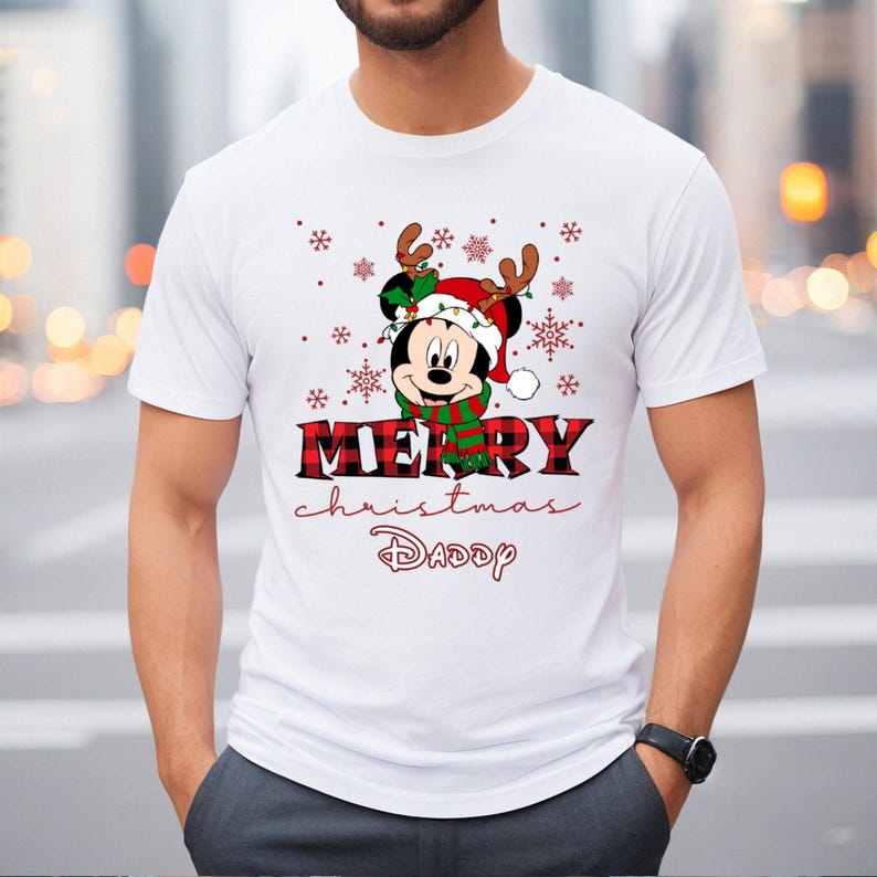 Op de afbeelding: Wit T-shirt met een rood-zwart ruitpatroon. Het ontwerp bevat een cartoon Mickey Mouse met een kerstmanmuts en rendiergewei. De tekst "Merry Christmas Daddy" staat onder de afbeelding.