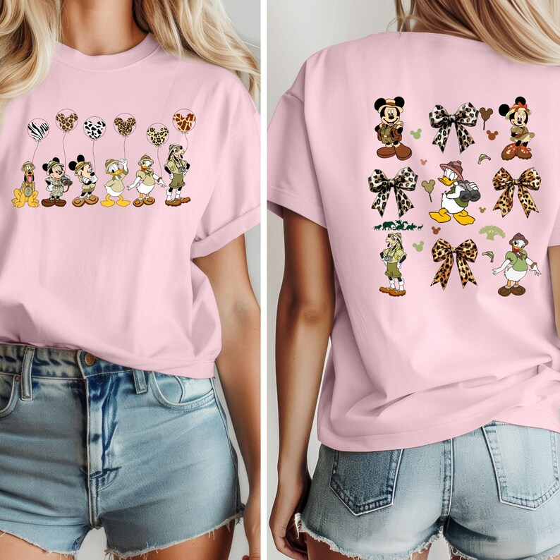 May include: Two pink t-shirts with a cartoon character design. The front shirt features a line of Disney characters with balloons. The back shirt features a variety of Disney characters with bows and a jungle theme.