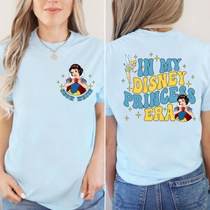May include: Light blue t-shirt with a graphic of Snow White on the front and the text "In My Disney Princess Era" on the back. The graphic on the back also includes a fairy and stars.