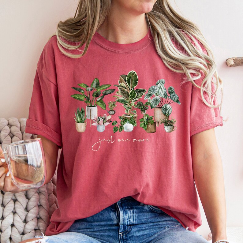 May include: A red t-shirt with a graphic of potted plants and the text "just one more".