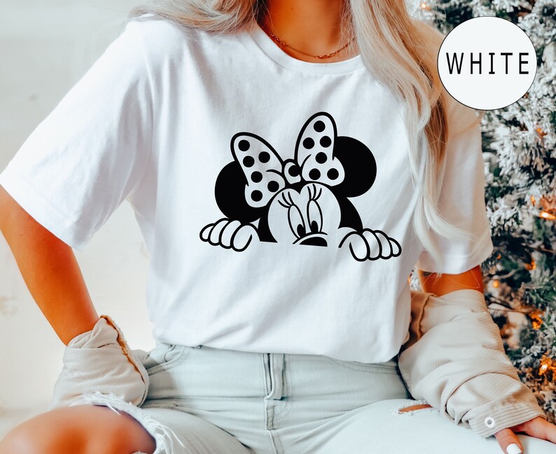 K&ouml;nnte beinhalten: Wei&szlig;es T-Shirt mit einem schwarz-wei&szlig;en Motiv von Minnie Maus, die hinter einer Oberfl&auml;che hervorlugt. Minnie Maus tr&auml;gt eine gepunktete Schleife.
