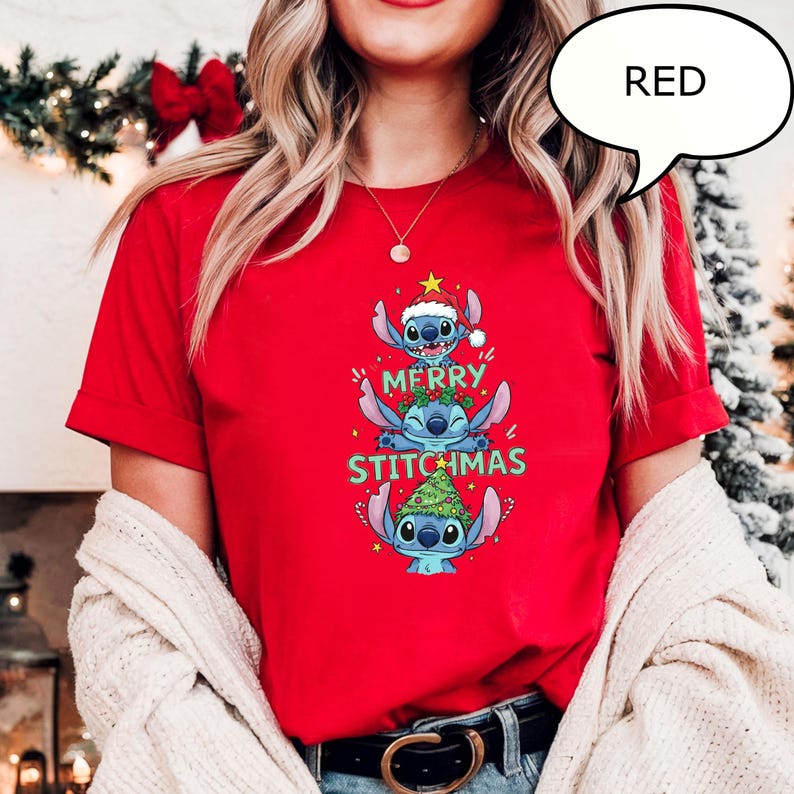 May include: A red t-shirt featuring a stacked design of the character Stitch from the movie Lilo & Stitch, with the text "MERRY STITCHMAS". Stitch is wearing a Santa hat and a Christmas tree. The word "RED" is in a speech bubble.