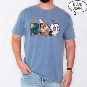 May include: A blue jean t-shirt featuring a cartoon graphic of characters from the film Moana spelling out the word "BRO".