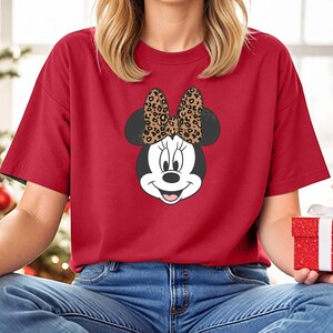 May include: Red t-shirt with a cartoon image of Minnie Mouse wearing a leopard print bow.