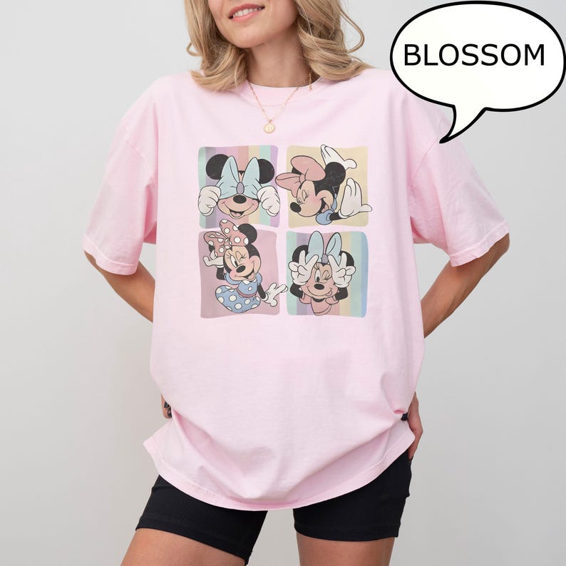 Puede incluir: Una camiseta rosa claro con un gr&aacute;fico de cuatro paneles de Minnie Mouse en varias poses. Cada panel tiene un fondo pastel. La palabra "BLOSSOM" est&aacute; en un bocadillo. La camiseta la lleva una persona.