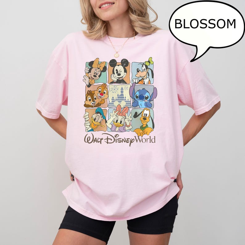 May include: A light pink t-shirt featuring a grid of Disney characters, including Mickey Mouse, Donald Duck, and Stitch. The words "Walt Disney World" are printed below the grid in a cursive font. A speech bubble with the word "BLOSSOM" is in the top right corner.