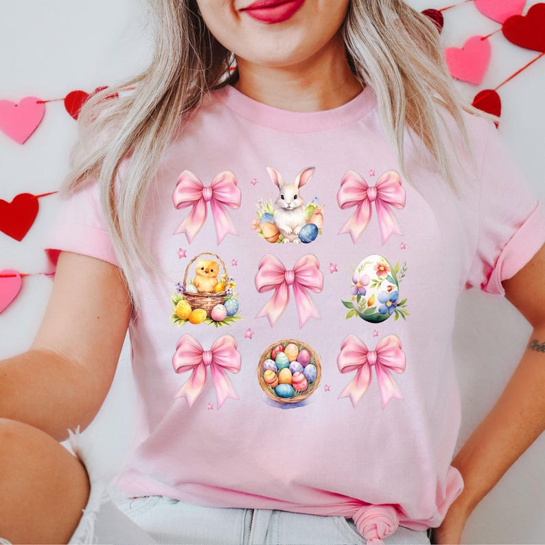 Puede incluir: Camiseta rosa con un dise&ntilde;o de Pascua pastel con un conejito, pollitos, huevos y lazos.