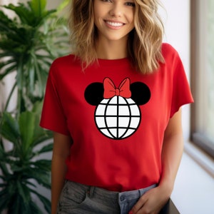 K&ouml;nnte beinhalten: Rotes T-Shirt mit einem schwarzen und wei&szlig;en Globus-Motiv mit einer roten Schleife oben, die an Mickey Mouse-Ohren erinnert.