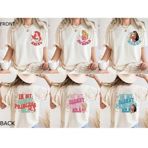 May include: Three white t-shirts with different Disney princess characters on the front. The back of the shirts all have the text "In My Disney Princess Era" with a princess character on each shirt.