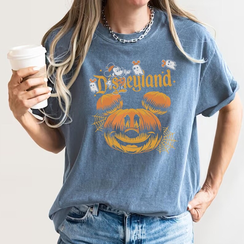 May include: A blue t-shirt with a vintage-style graphic of Mickey Mouse dressed as a pumpkin with the text "Disneyland" above it.