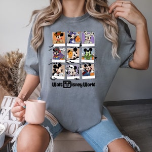 以下が含まれることがあります： グレーのTシャツに、ハロウィンのコスチュームを着たミッキーマウスとその仲間たちのグラフィックがプリントされています。グラフィックは9つの正方形のグリッドになっており、その下に「Walt Disney World」の文字があります。