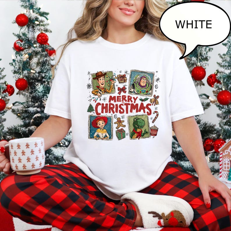 May include: White t-shirt featuring a colorful graphic with characters and the text "MERRY CHRISTMAS". The design includes images of Woody, Buzz Lightyear, Jessie, and Rex. The shirt is part of a Christmas-themed collection.