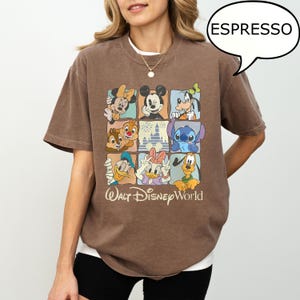 May include: Espresso-colored t-shirt featuring a grid of Disney characters including Mickey Mouse, Minnie Mouse, Donald Duck, and Stitch. The shirt has the text "Walt Disney World" in a vintage style.