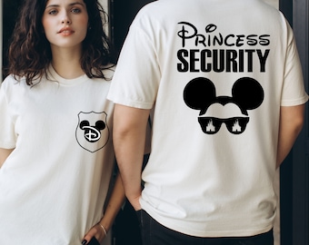 Op de afbeelding: Een wit T-shirt met een zwart Mickey Mouse-hoofd dat een zonnebril draagt met een kasteelontwerp. De tekst "Princess Security" is op het shirt gedrukt.