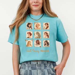 May include: A light blue t-shirt with a graphic of nine Disney princesses in frames. The text "Walt Disney World" is printed below the graphic.