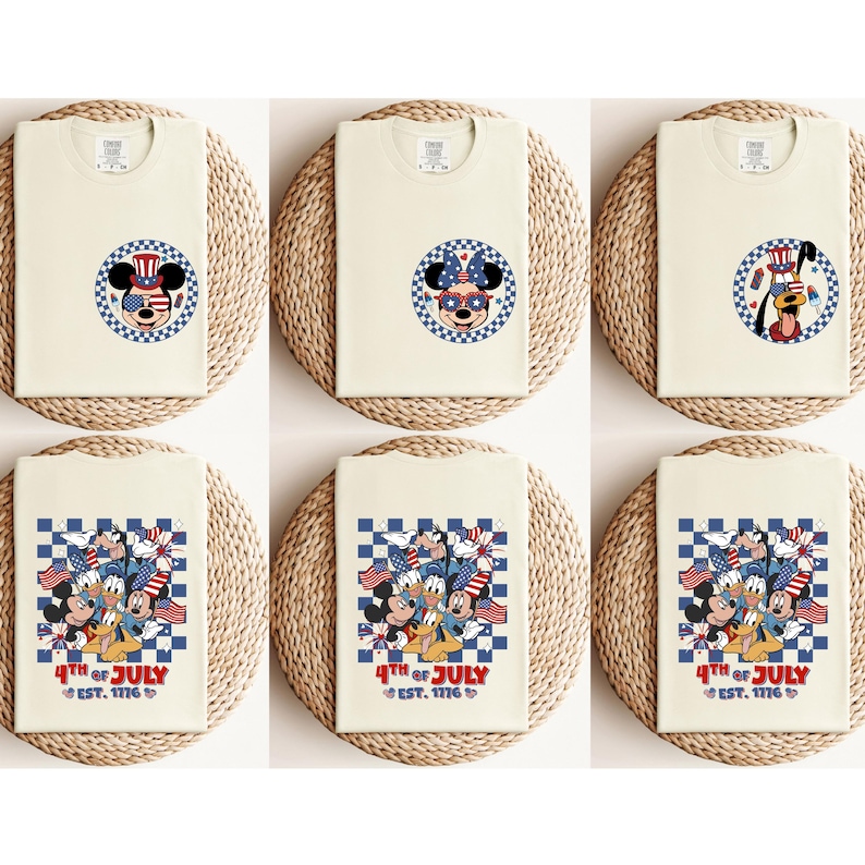 Pode incluir: T-shirts creme com designs patri&oacute;ticos com Mickey Mouse, Minnie Mouse e Pluto. Os designs incluem elementos vermelhos, brancos e azuis e o texto "4th of July EST. 1776". As camisas s&atilde;o exibidas em esteiras tecidas.