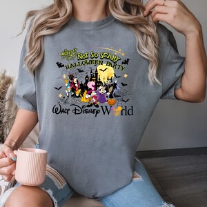 May include: Gray t-shirt with a graphic of Mickey Mouse and friends in a Halloween scene. The text reads "Mickey's Not So Scary Halloween Party Walt Disney World".