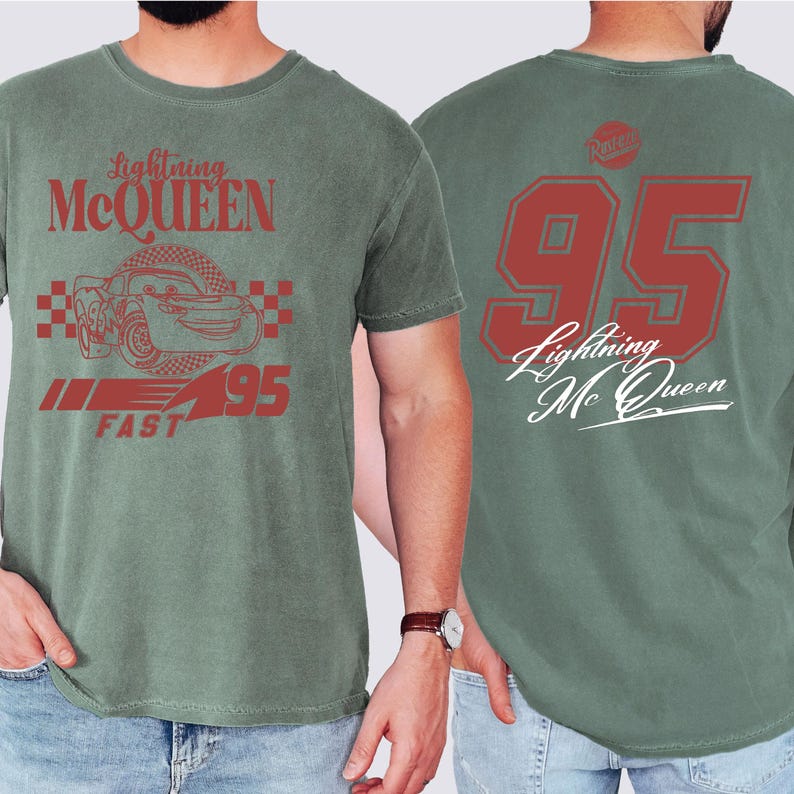 May include: Green t-shirt with a red graphic of Lightning McQueen from the Cars movie. The front of the shirt features McQueen's race car number 95 and the words "Lightning McQueen" and "Fast". The back of the shirt features the number 95 and the words "Lightning McQueen".