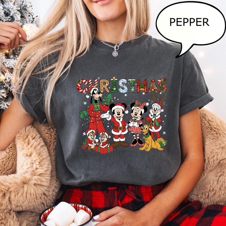 May include: Dark grey t-shirt with a festive Christmas design. The word "CHRISTMAS" is written across the front in colourful letters. The design features cartoon characters including Mickey and Minnie Mouse, Goofy, Pluto, and Chip and Dale.