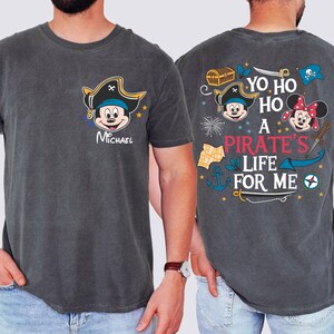 May include: Two grey t-shirts with a Mickey Mouse pirate theme. One shirt has a Mickey Mouse pirate with the text "Yo Ho Ho A Pirate's Life For Me". The other shirt has a Mickey Mouse pirate with the text "Michael".