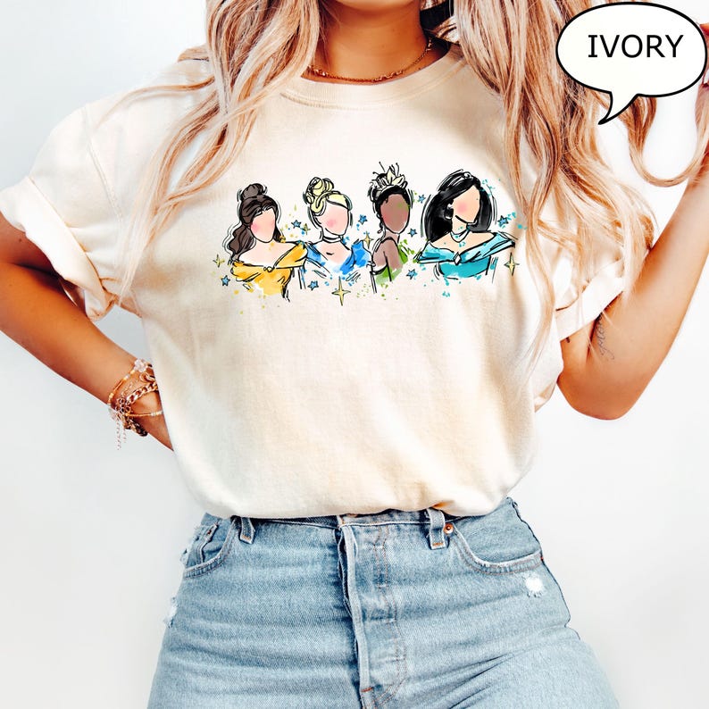 May include: Ivory-colored t-shirt featuring a watercolor illustration of four women in gowns. The women are depicted with various hairstyles and skin tones, surrounded by small star accents. The word "IVORY" is in a speech bubble.