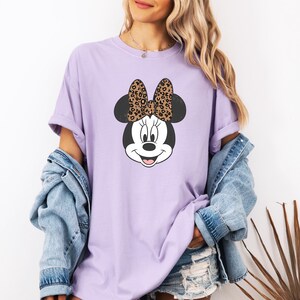 May include: A lavender t-shirt with a cartoon image of Minnie Mouse wearing a leopard print bow.
