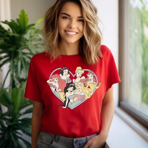 Pu&ograve; includere: Maglietta rossa con un design a forma di cuore che presenta sette principesse Disney. Le principesse sono Biancaneve, Cenerentola, Ariel, Jasmine, Belle, Aurora e Mulan.