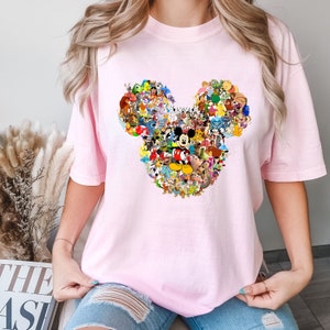 May include: A pink t-shirt with a graphic of Mickey Mouse's head made up of many different Disney characters.