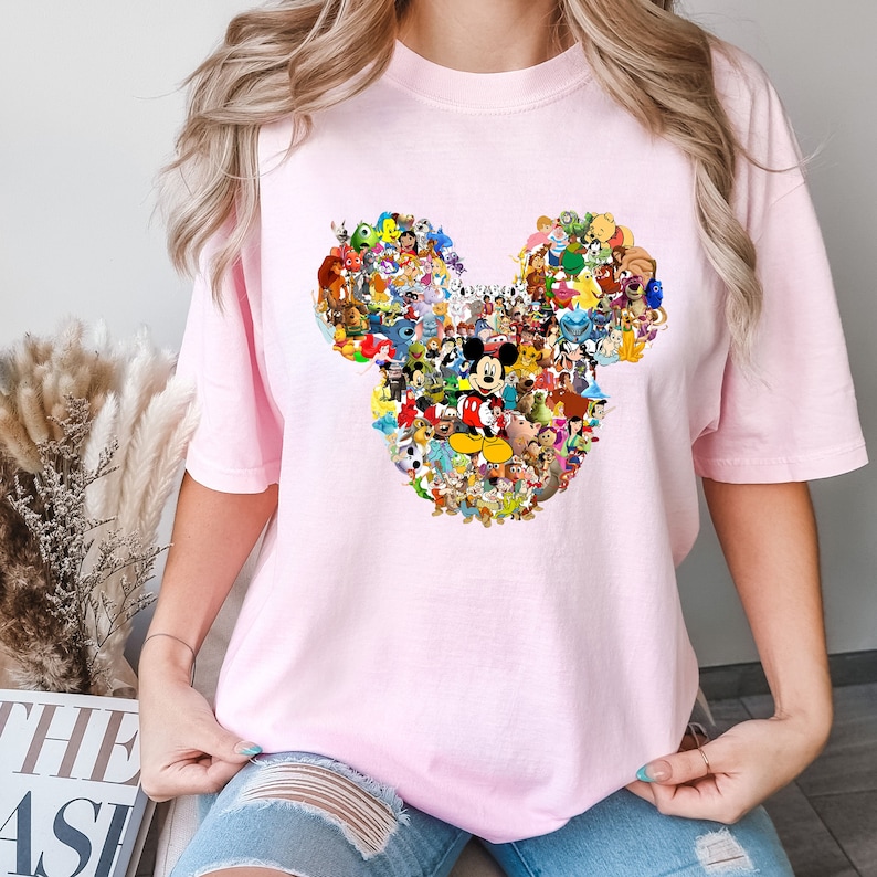 May include: A pink t-shirt with a graphic of Mickey Mouse's head made up of many different Disney characters.